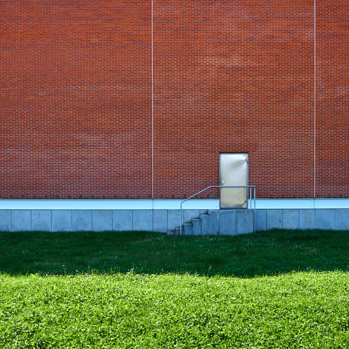 backsteinmauer-mit-metalltuer-und-wiese-architektur