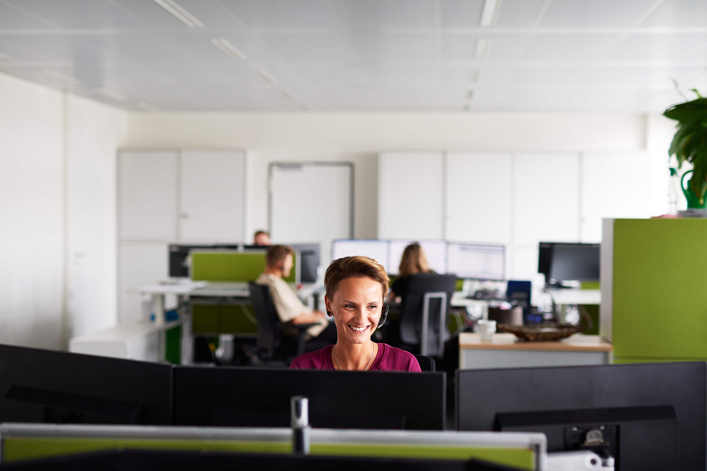 business-portrait-von junger-disponentin-die-im-grossraum-buero-vor-dem-computer-sitzt