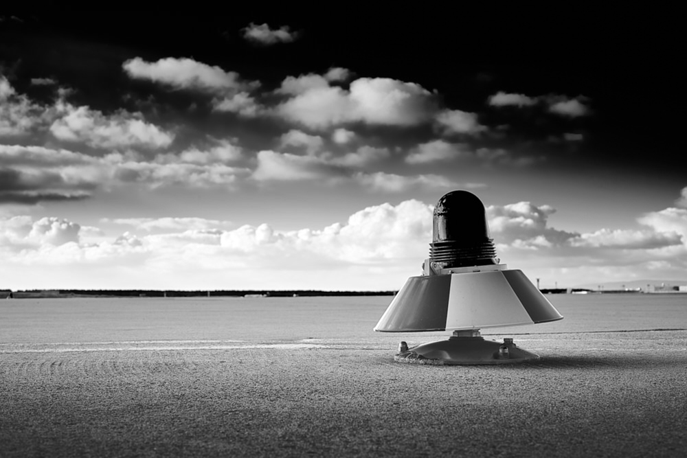 fine-art-fotografie-landebahn-mit-signalleuchte-am-flughafen-in-schwarz-weiß